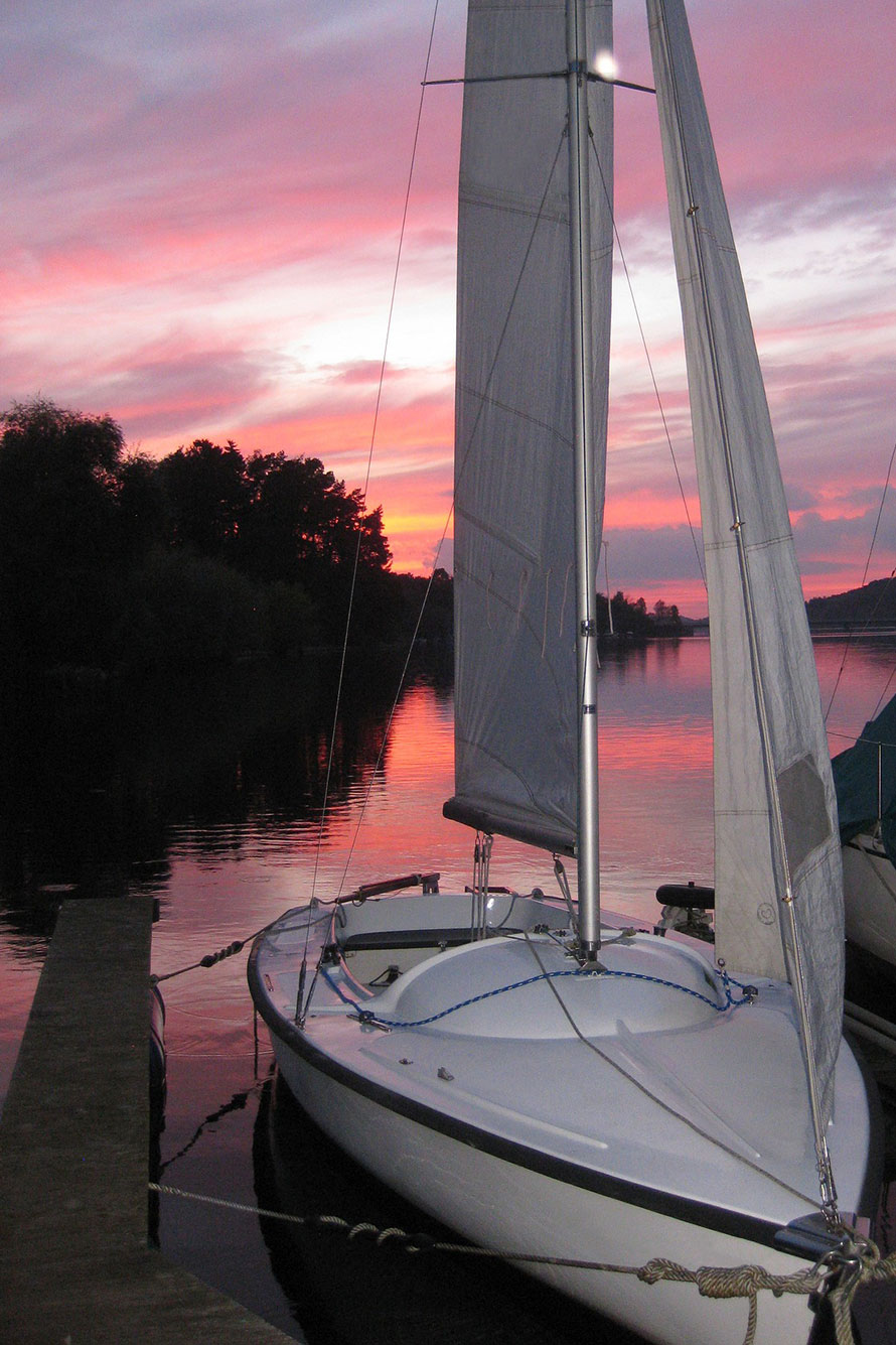 Aufgetakelte Segeljolle am Steg in der Abenddämmerung