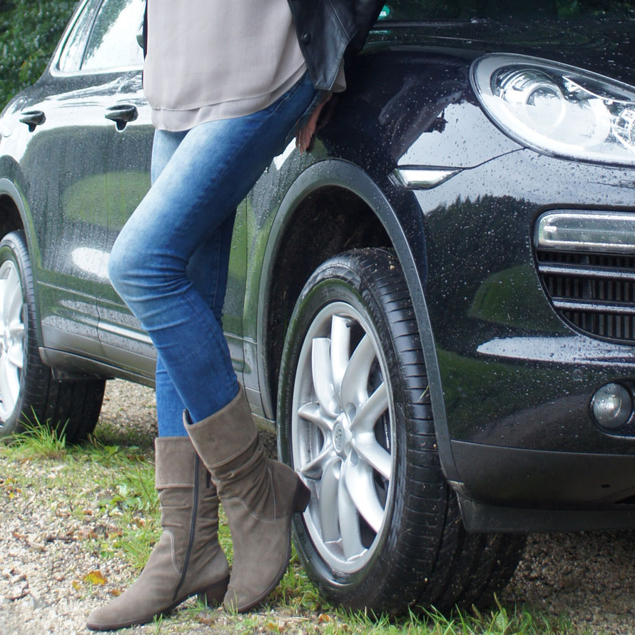 Symbolbild: Frau in Jeans lehnt an Auto.