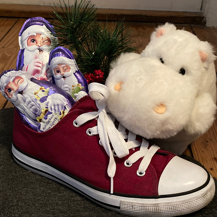 Roter Sneaker mit Schoko-Nikolaus-Figuren und Plüschtier vor der Wohnungstür in einem Altbauflur