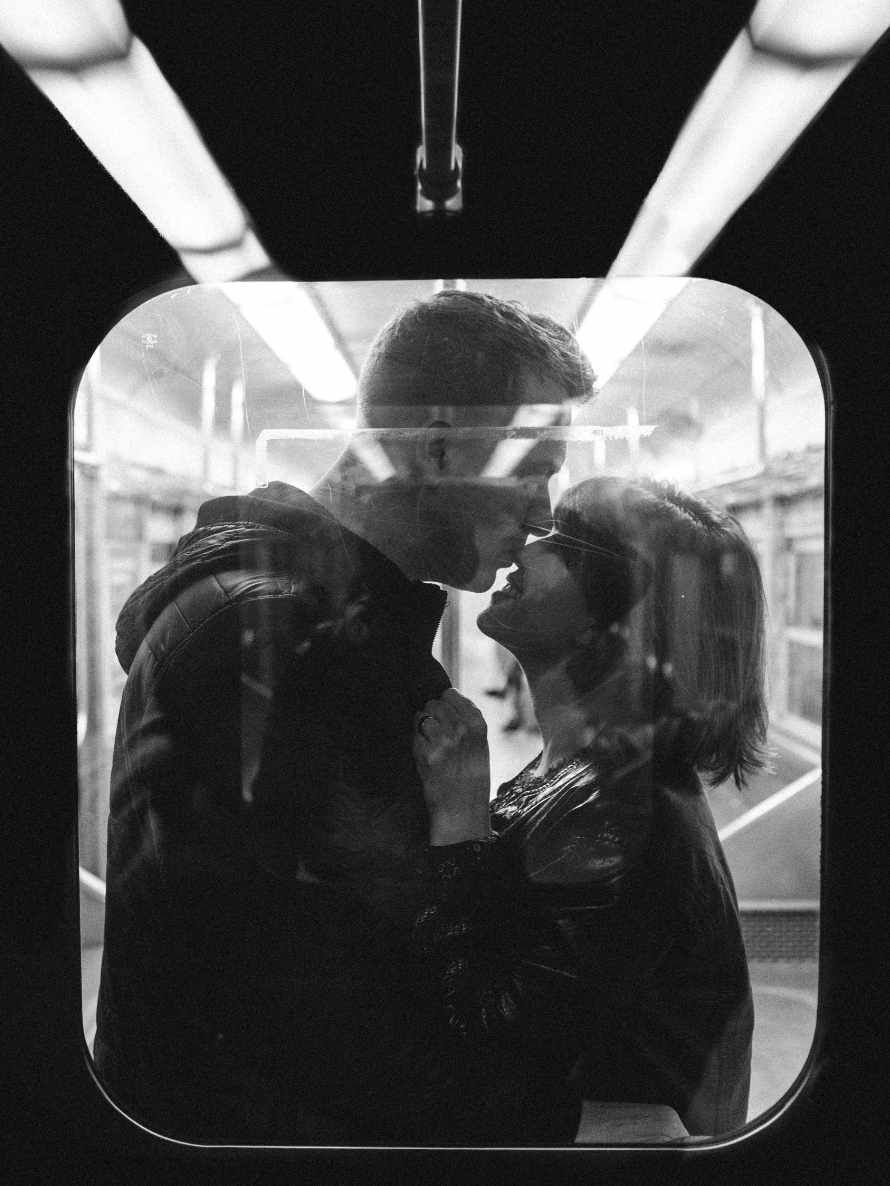 Mann und Frau küssen sich, fotografiert durch die Tür eines Zugabteils