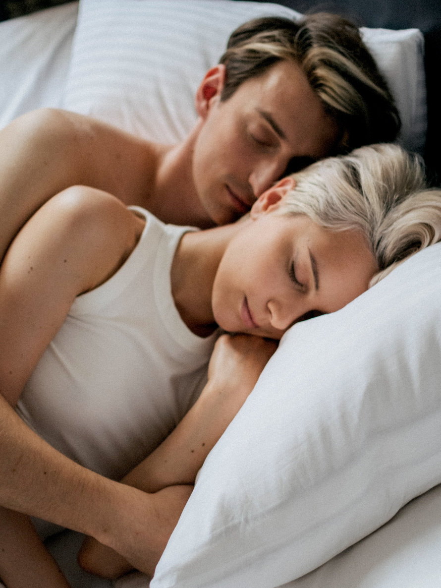 Paar schläft In Löffelchenstellung aneinandergekuschelt im Bett