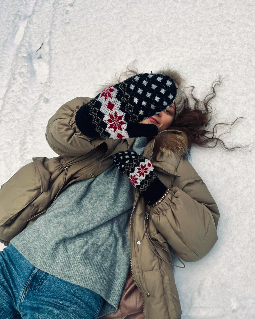 Frau liegt auf dem Rücken im Schnee