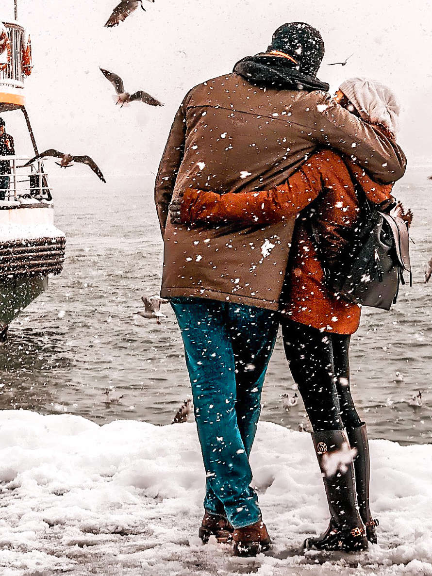Paar wartet im dichten Schneetreiben am Hafen.