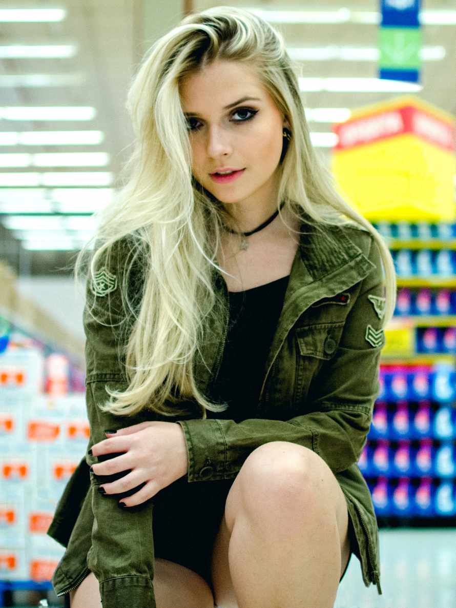 Junge blonde Frau hockt im Supermarkt auf dem Boden.