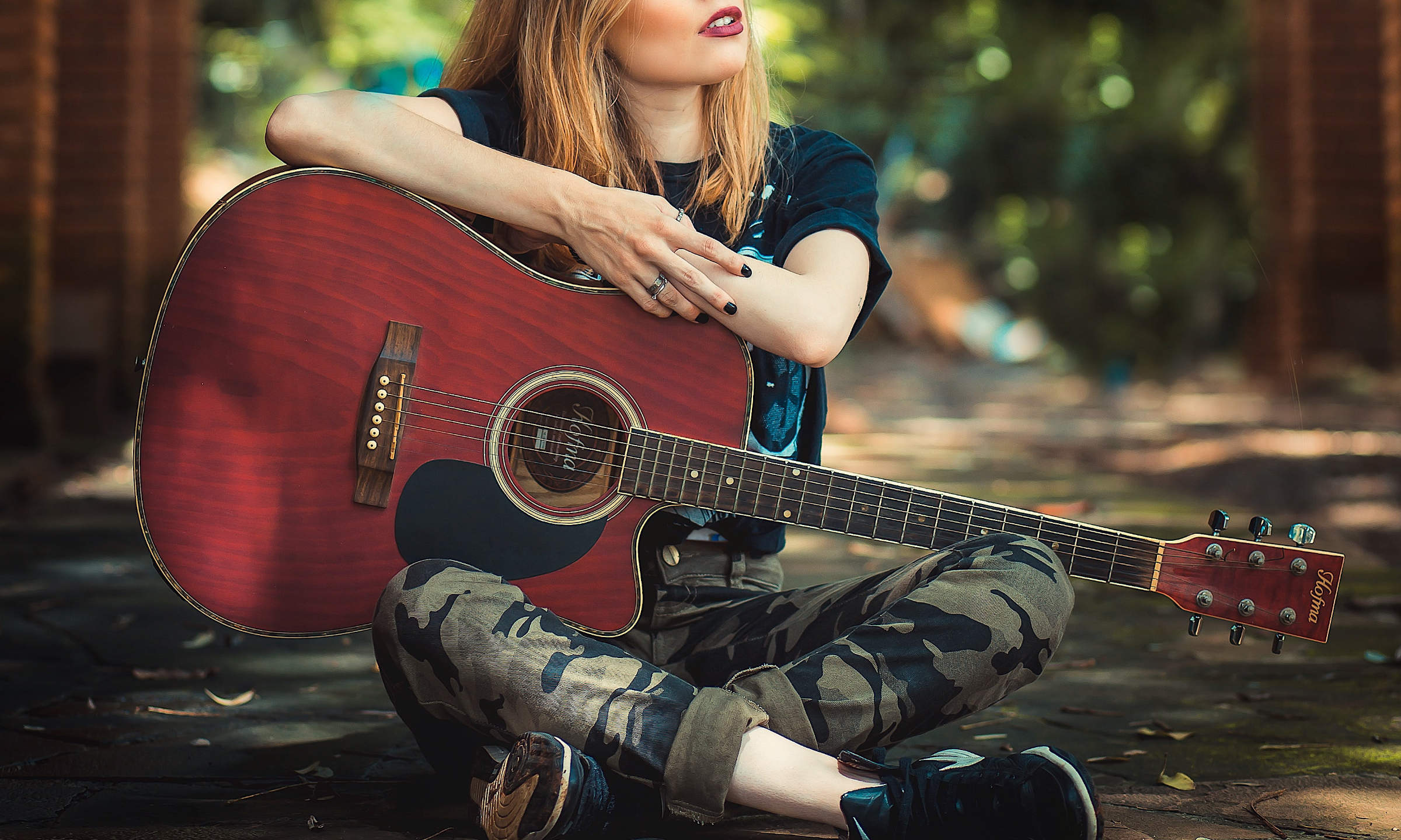 Junge Frau spielt im Wald Gitarre