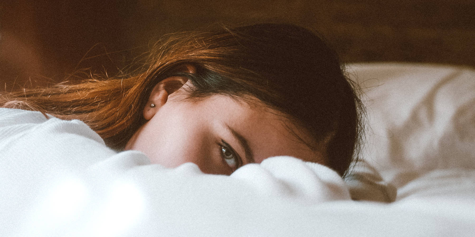 Brünette Frau liegt auf dem nassen Bett.