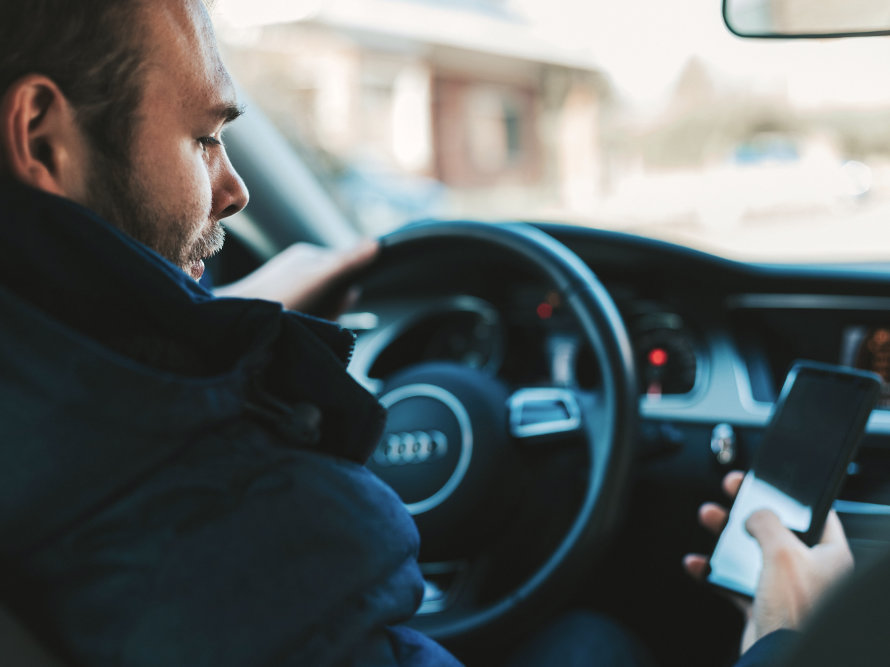 Mann schat im Auto sitzend auf sein Smartphone