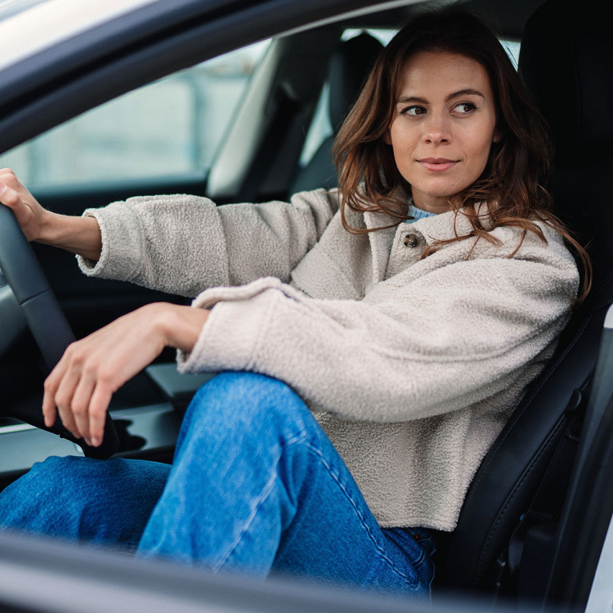 Frau sitzt bei geöffneter Tür im stehenden Auto