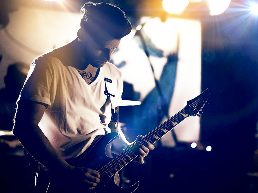 Musiker mit Gitarre beim Konzert auf der Bühne.