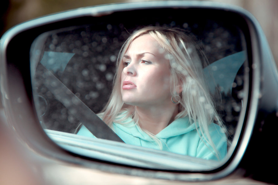 Verzweifelte Blondine im Rückspiegel eines Autos