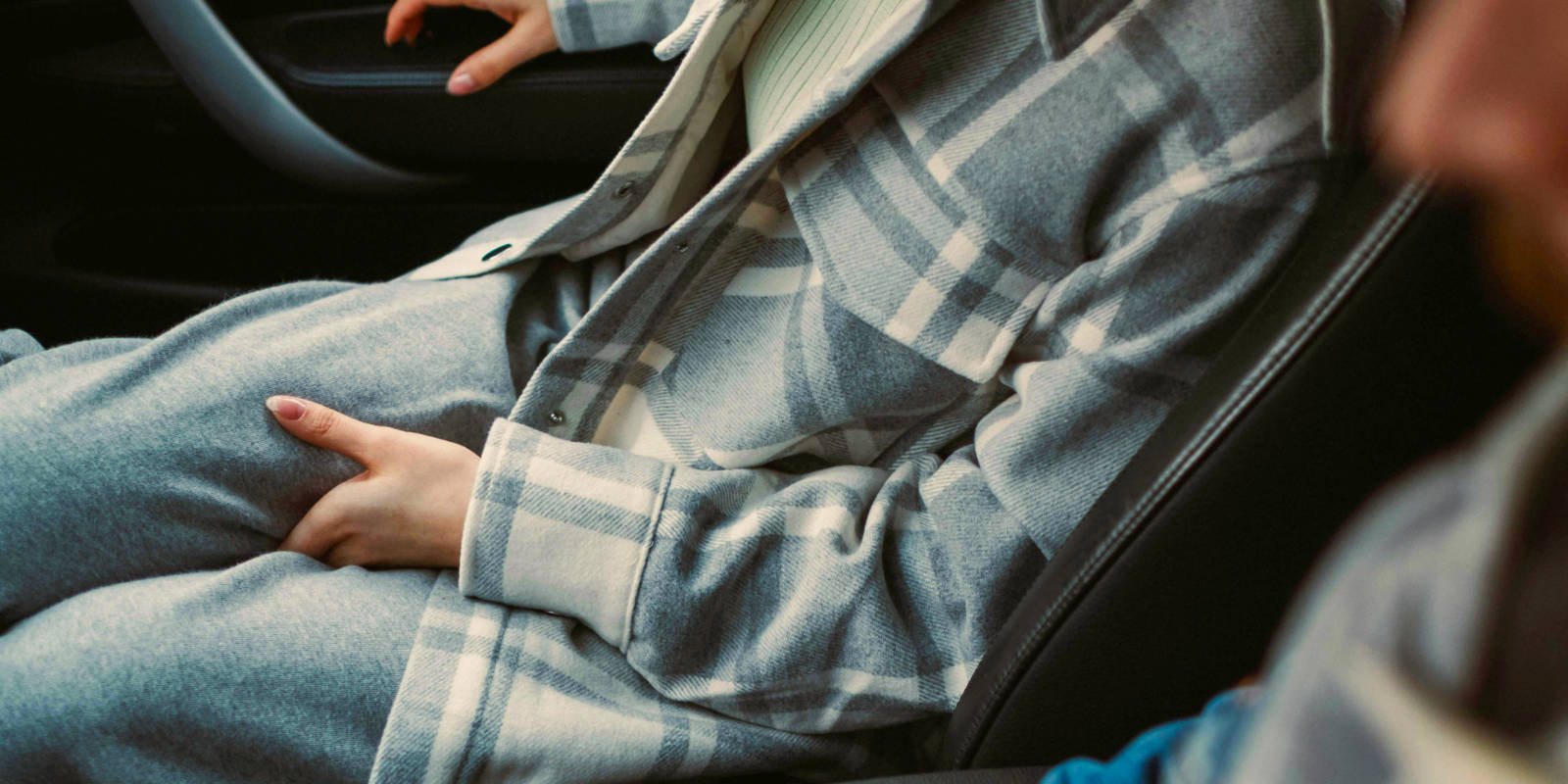 Frau sitzt dringend müssend auf dem Beifahrersitz im Auto.