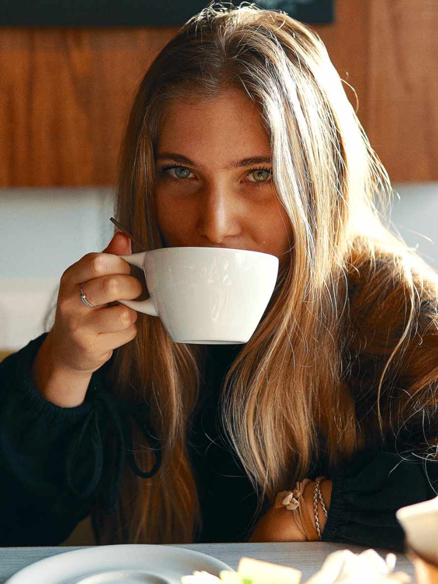 Gegenüber sitzende schöne Frau trinkt Kaffee