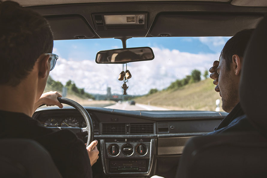 Zwei junge Männer unterwegs im Auto auf der Autobahn