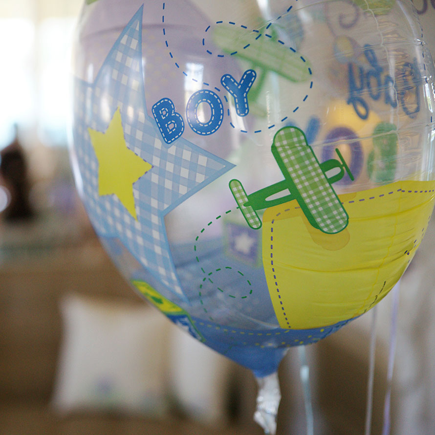 Durchsichtiger Luftballon mit der Aufschrift „Boy“ und aufgedrucktem Flugzeugmotiv“ in gemütlich dekoriertem Zimmer