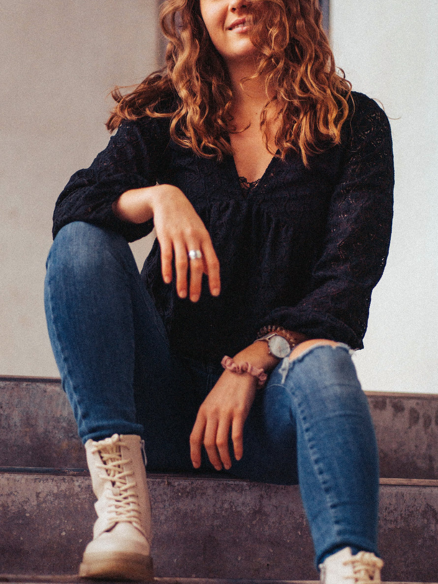 Frau in Jeans sitzt auf Betontreppe